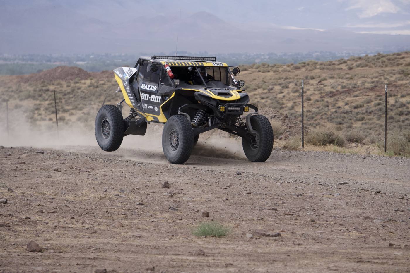 A yellow and black side-by-side on a dirt road